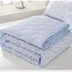 Folded blue floral quilt on bed