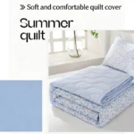 Folded light blue floral summer quilt on bed