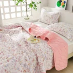 Cozy bed with floral bedding and pink quilt